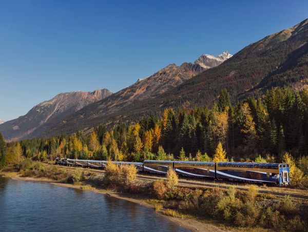 Rocky Mountaineer train travelling through the Canadian Rockies surrounded by dramatic mountain scenery.