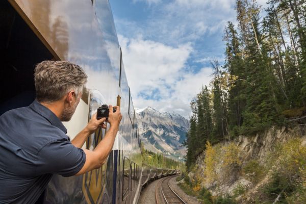 Man photographing the Rocky Mountains from onboard the Rocky Mountaineer train.